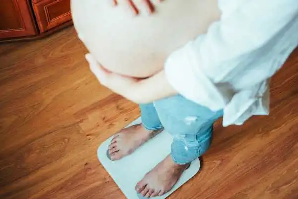 Image of woman weighing herself and experiencing weight gain through pregnancy Thetford